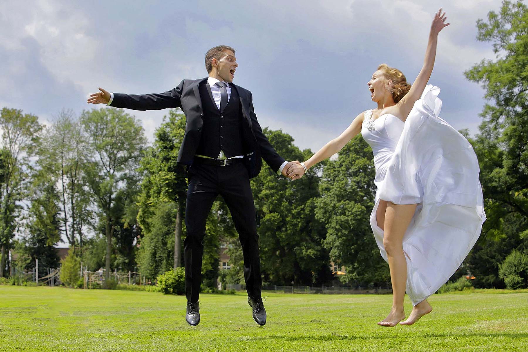 Fröhliches Brautpaar springt im Park – Hochzeit Fotograf Düsseldorf Chris Göttert für emotionale Hochzeitsfotos